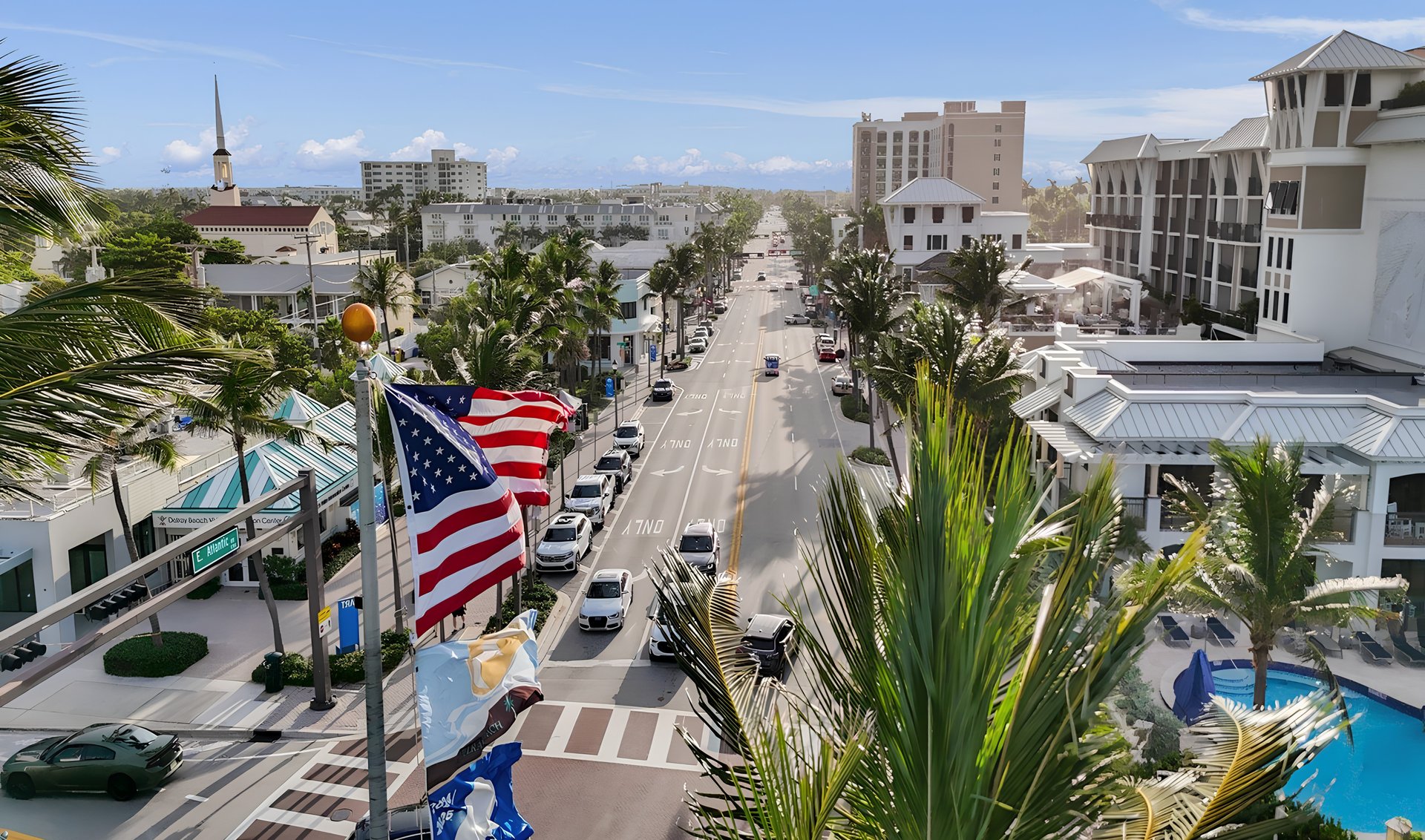 Palm-lined E Atlantic Avenue in Delray Beach, viewed above the street and surrounding shops.