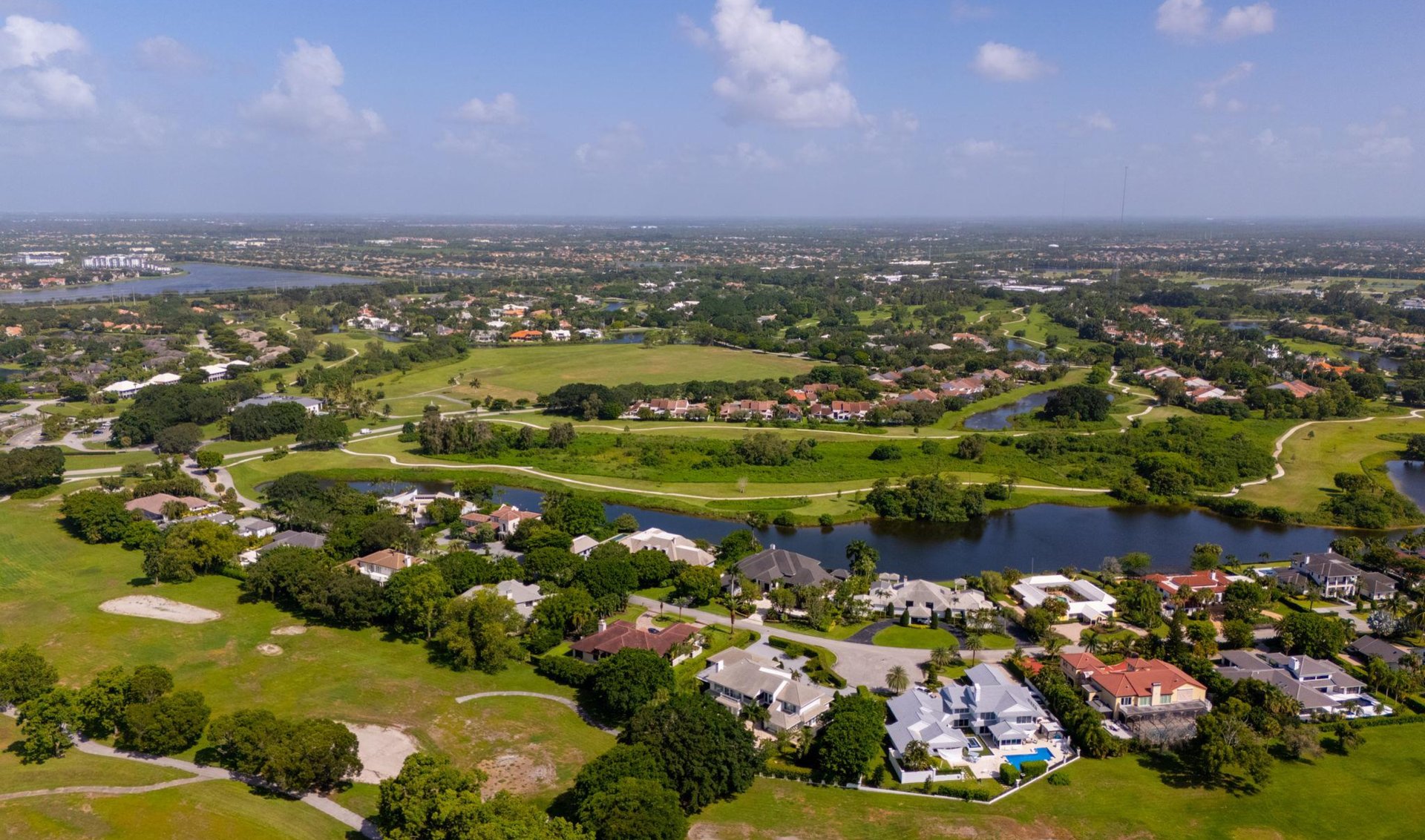 Aerial view of homes and open green space beside ponds and winding paths.