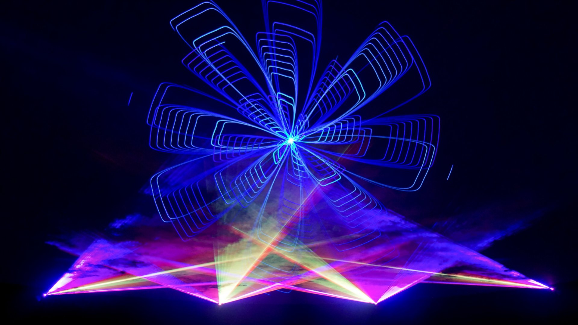 Laser light show with blue geometric flower pattern and colorful pink purple beams creating immersive visual display, Miami entertainment by The Edit Real Estate