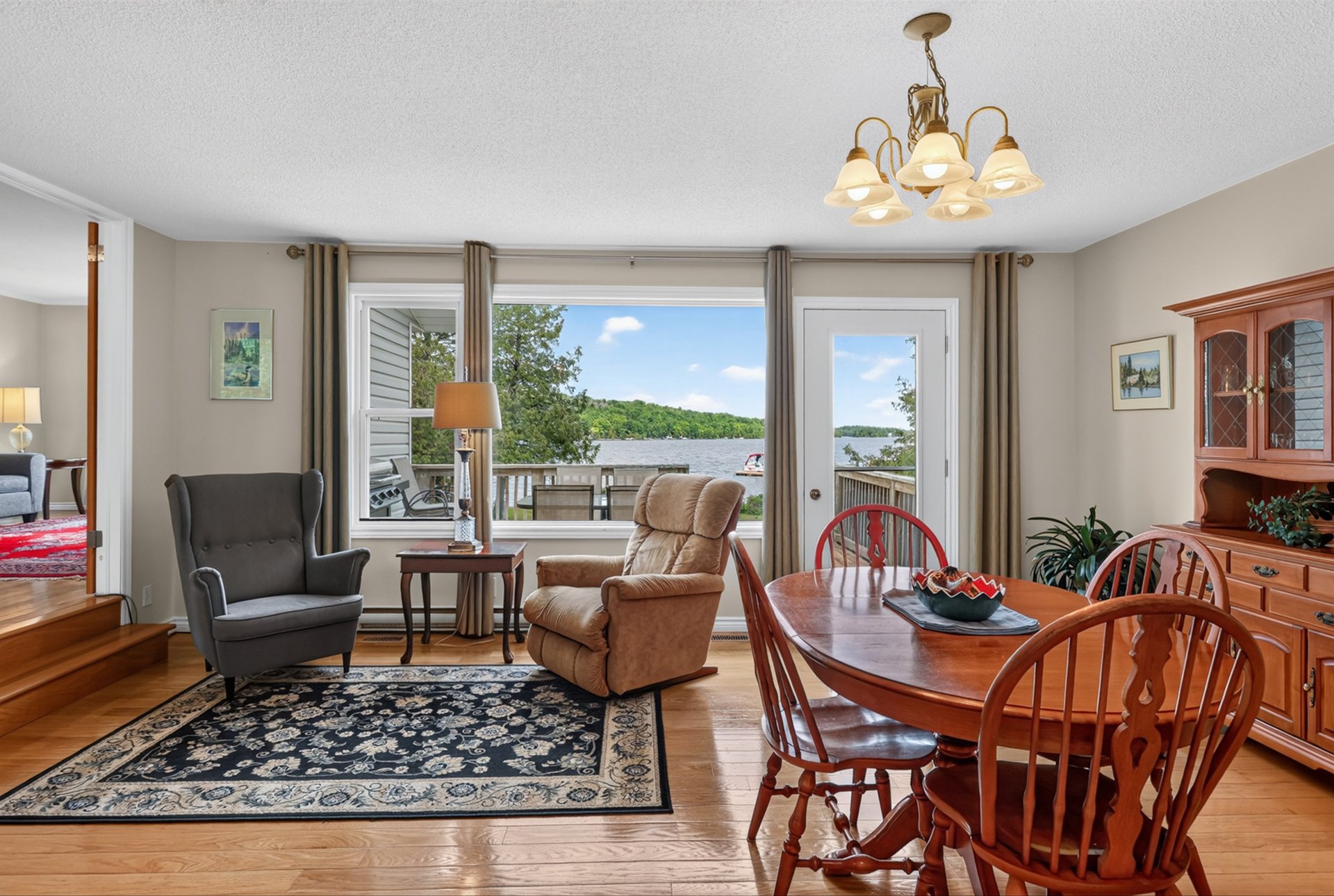 Dining and sitting area with hardwood floors and lake views through a large window.