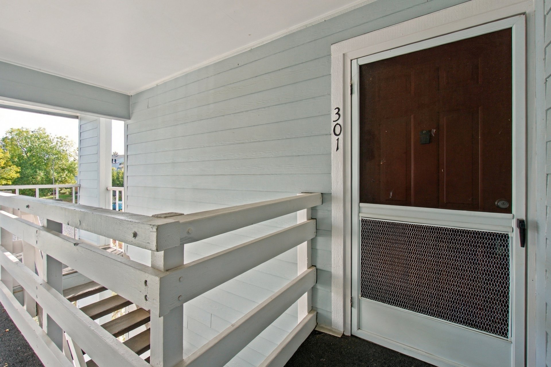 Condominium entrance with a brown door marked 301 and white wooden railing.