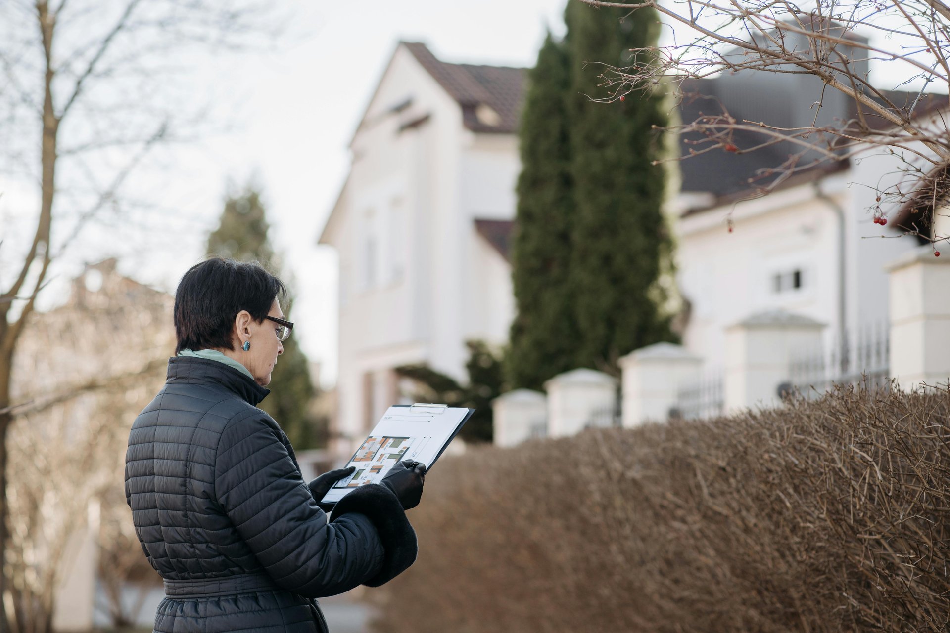 a woman standing on street while holding a house plan