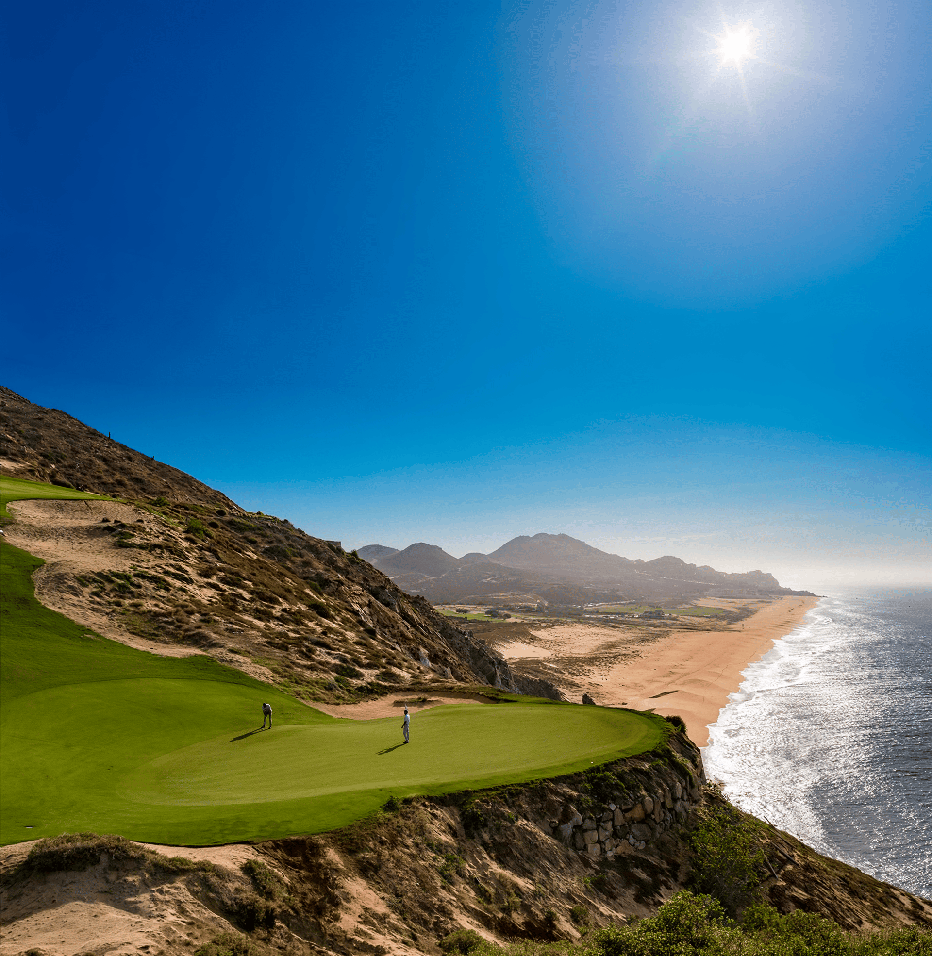 Golfers on an oceanfront green at Quivira Golf Club above the beach in Cabo San Lucas