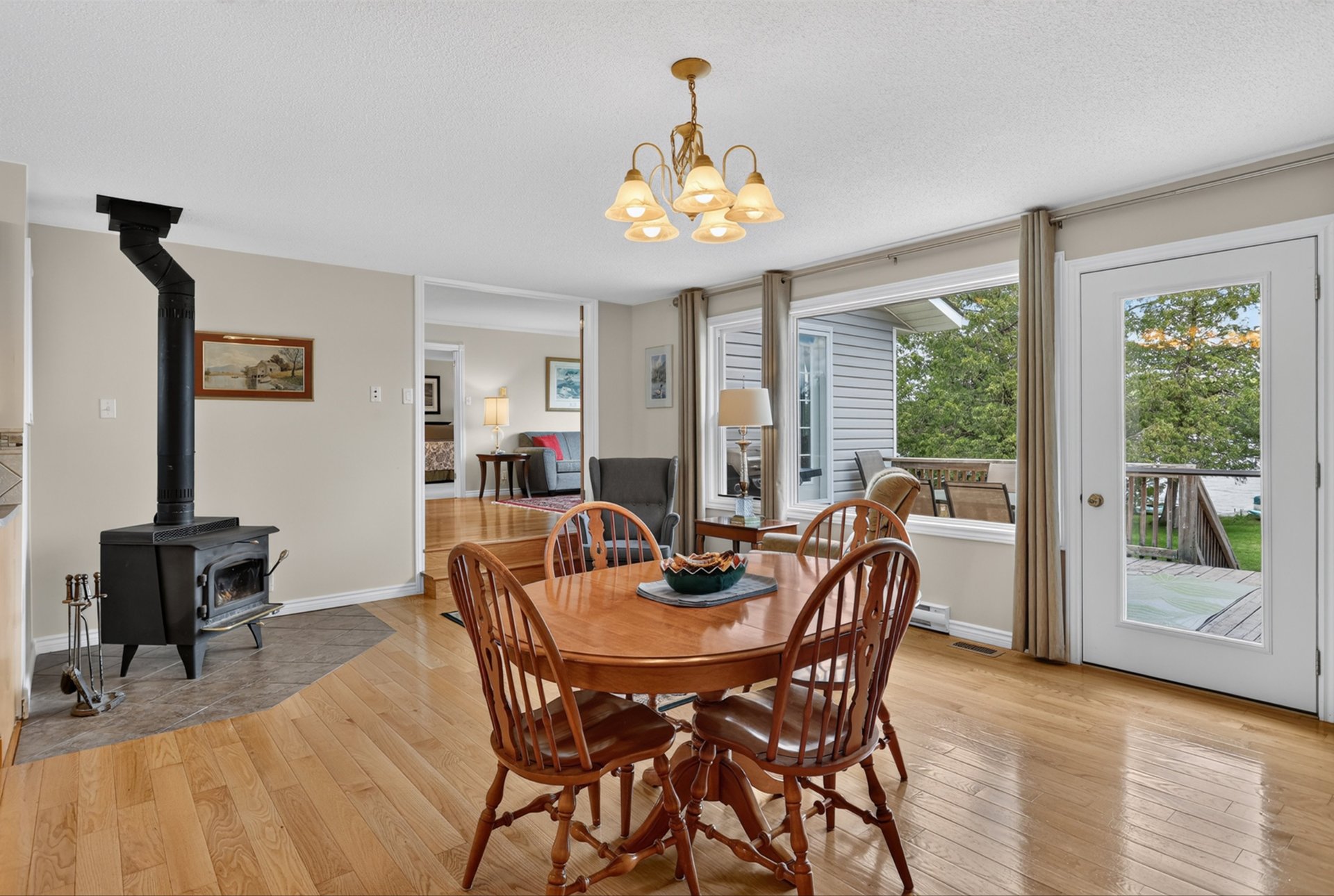 Dining room with a wood table, black stove, and glass door to the deck.