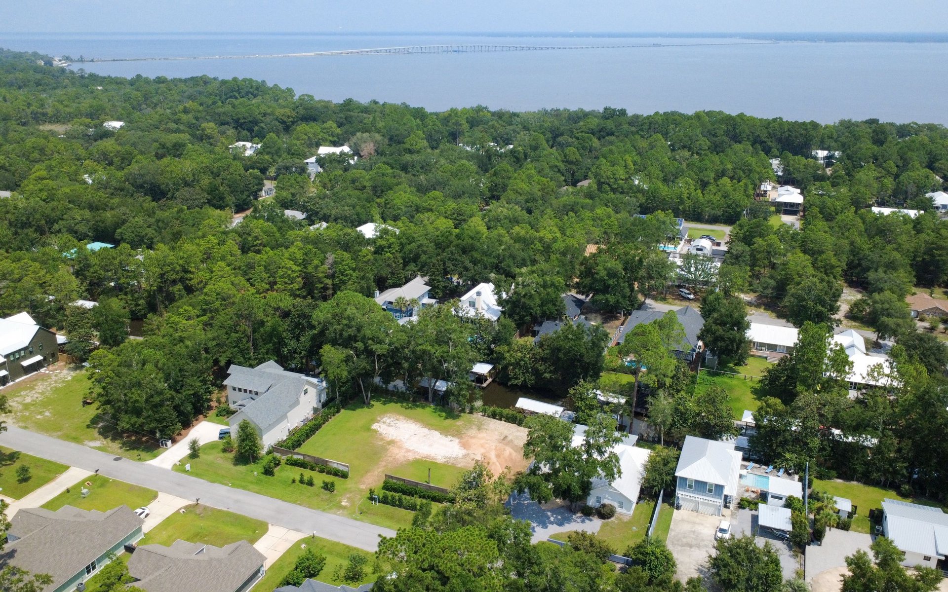 Waterfront neighborhood with homes among trees and a long bridge across the water