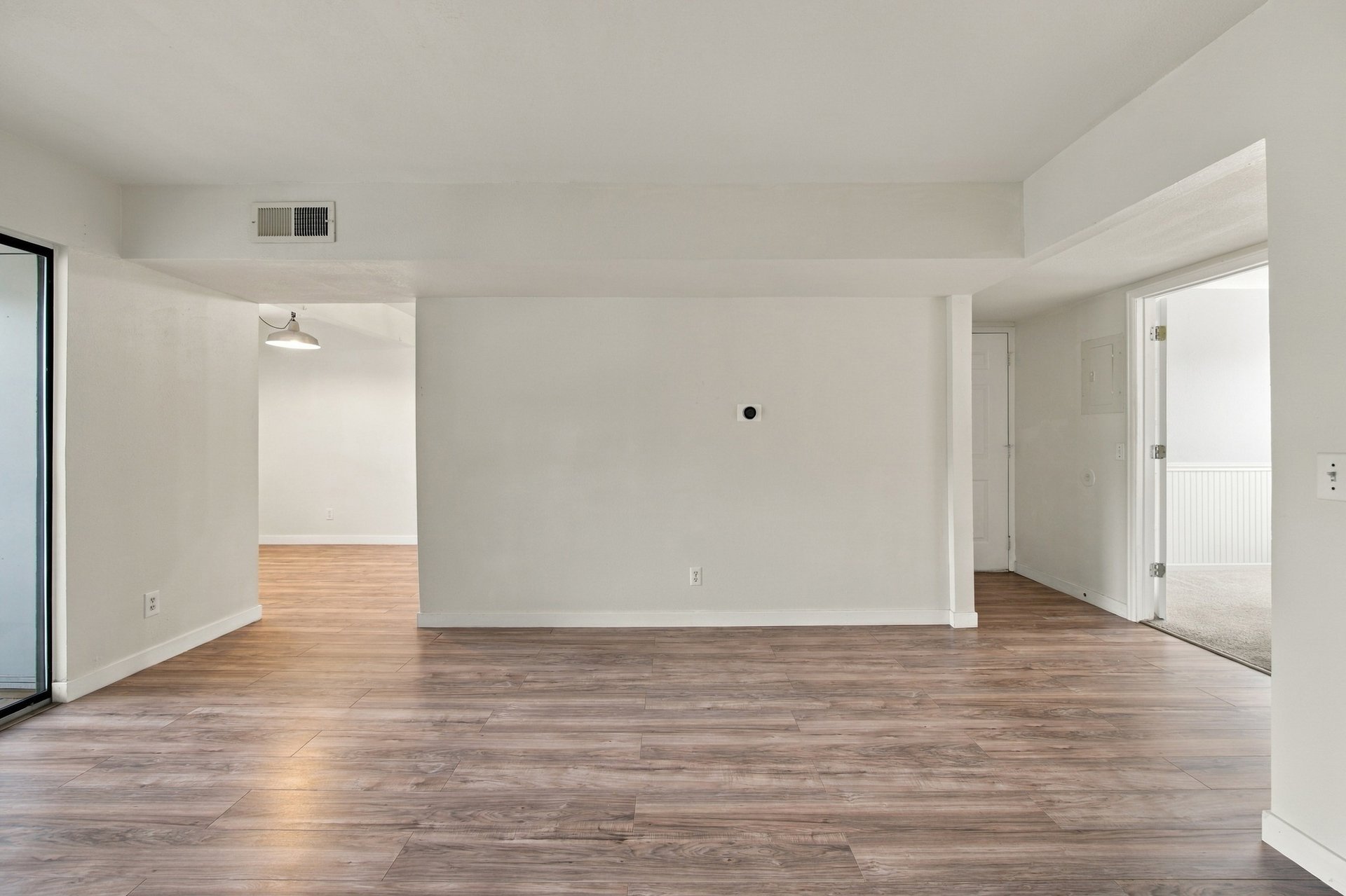 Empty living room with wood-look flooring and a sliding glass door.