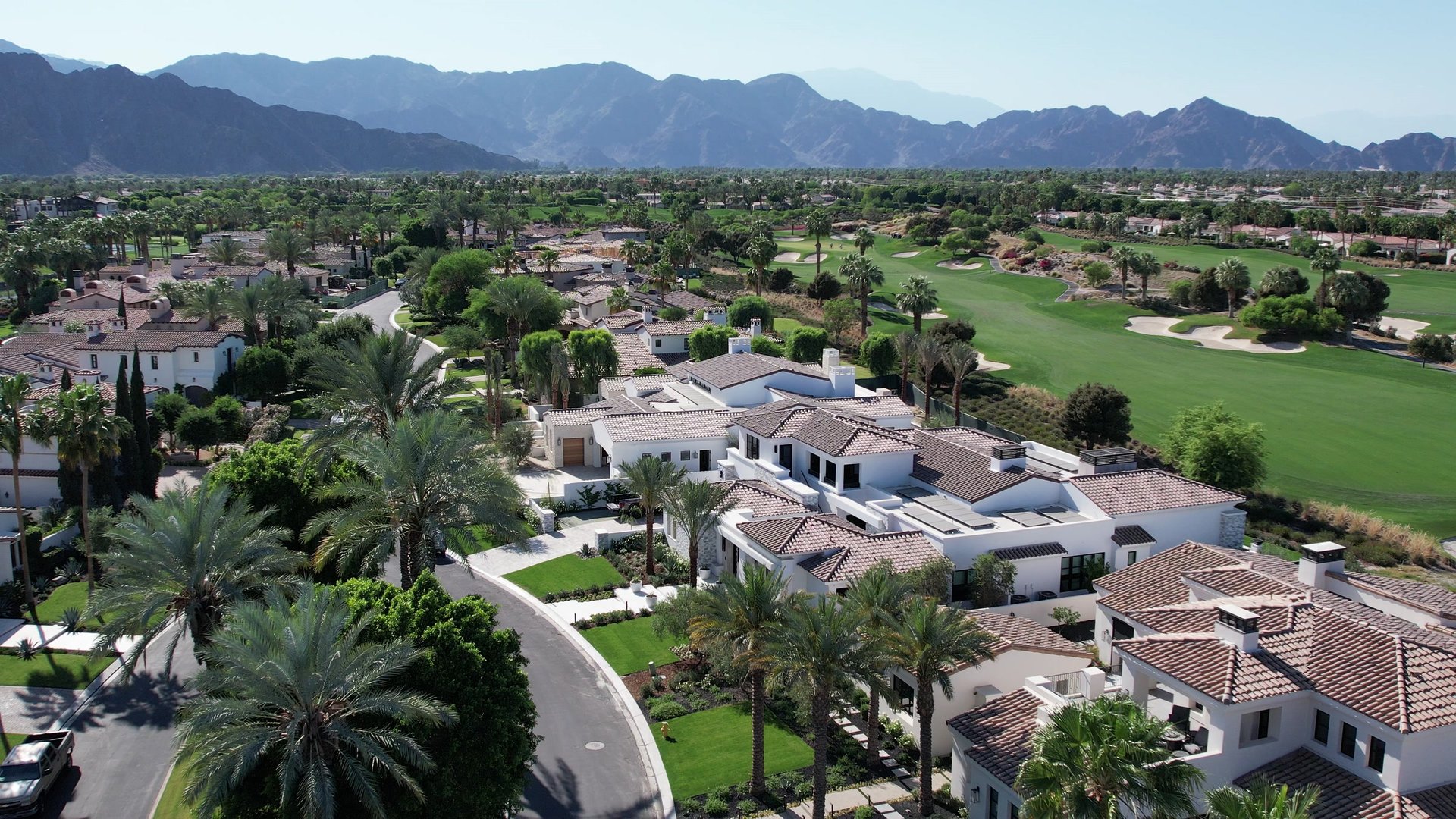 Aerial view across The Madison Club in La Quinta with golf courses, lakes, homes, and the Santa Rosa Mountains