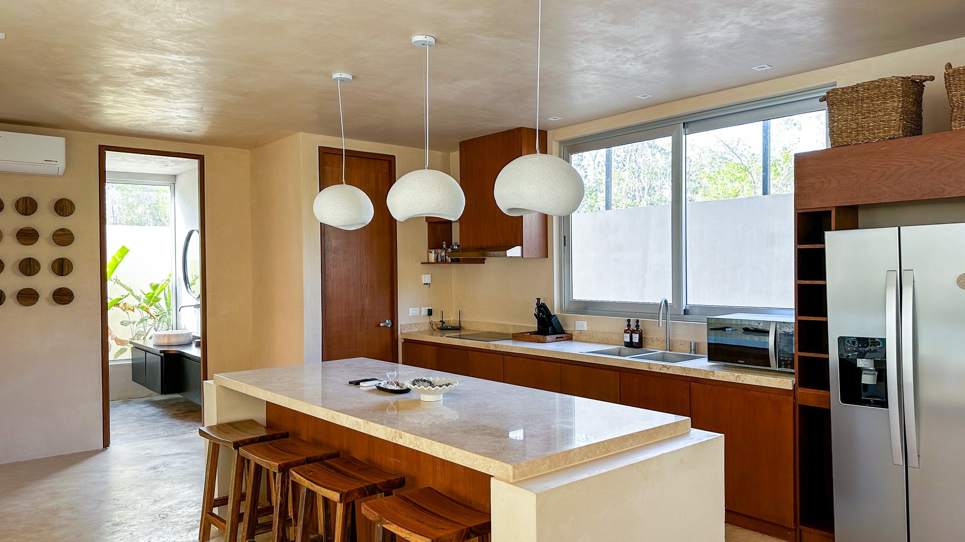 Kitchen with a large stone island, warm wood cabinetry, and broad windows.