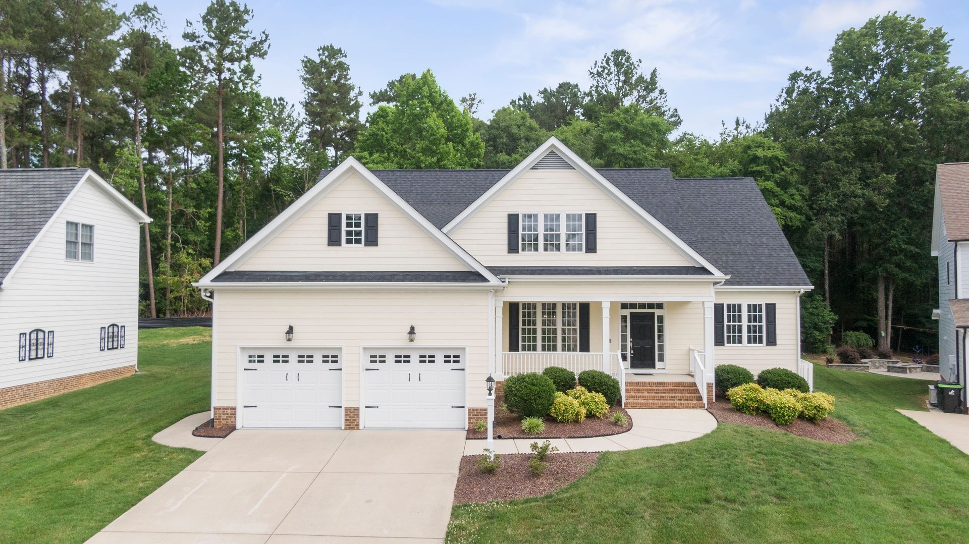 white and blue house with well manicured lawn and surrounded by mature trees