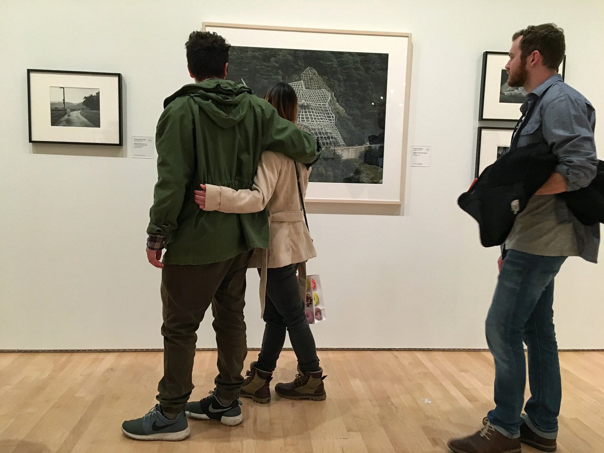 Couple with arms around each other viewing a large framed photograph in a bright gallery at SFMOMA.