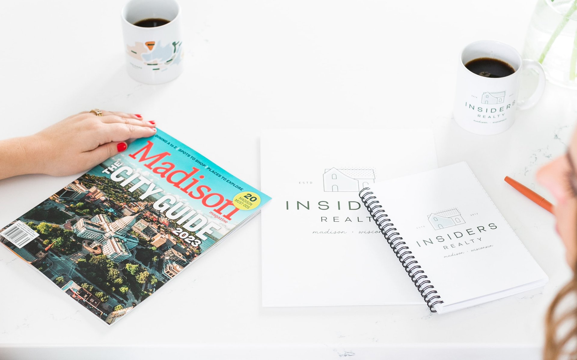 Exclusive preview of the Madison The City Guide 2023 magazine, accompanied by Insiders Realty products displayed on a table.