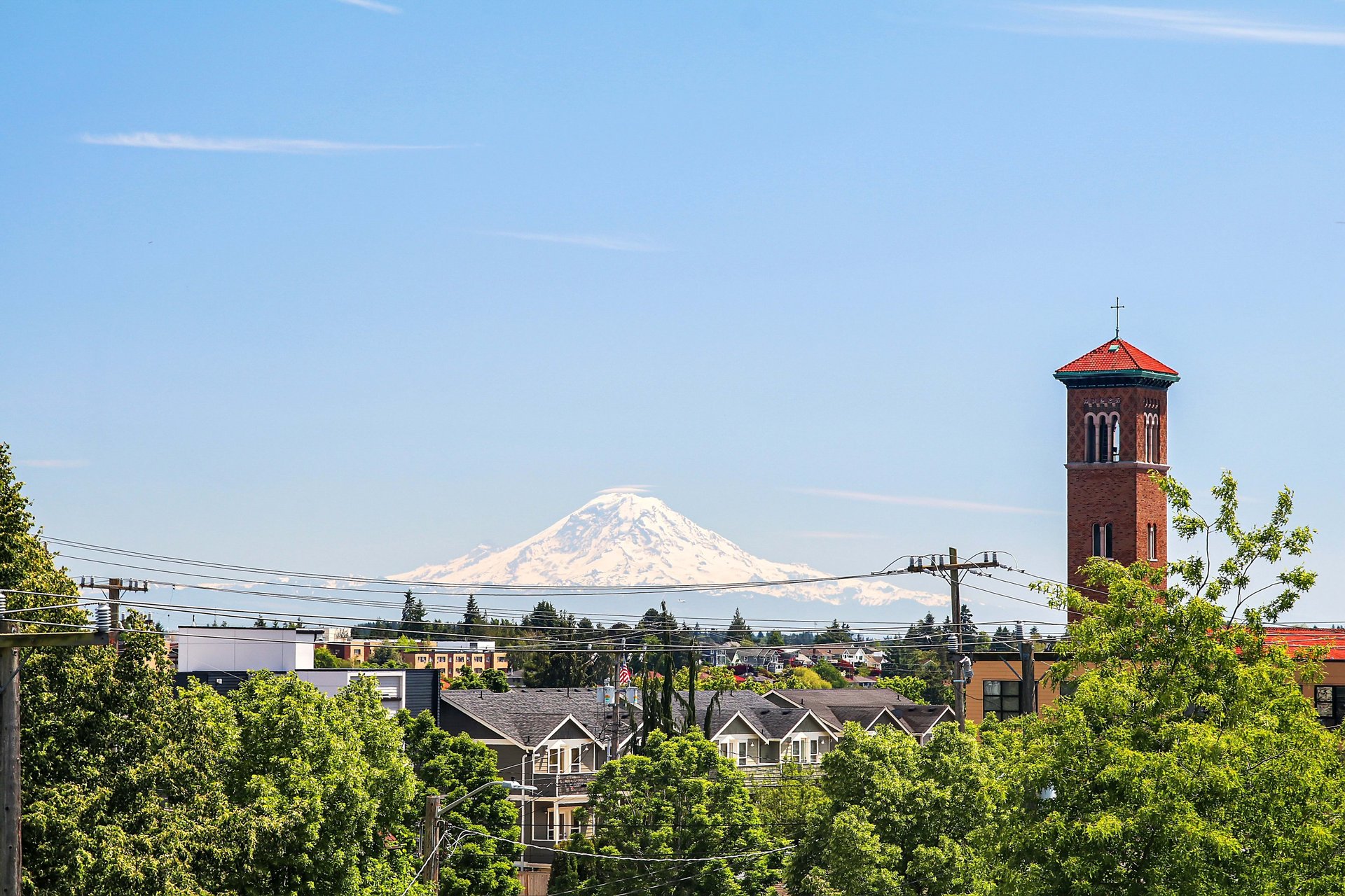 Seattle neighborhood with Mount Rainier in the distance and a red-brick tower above the trees.