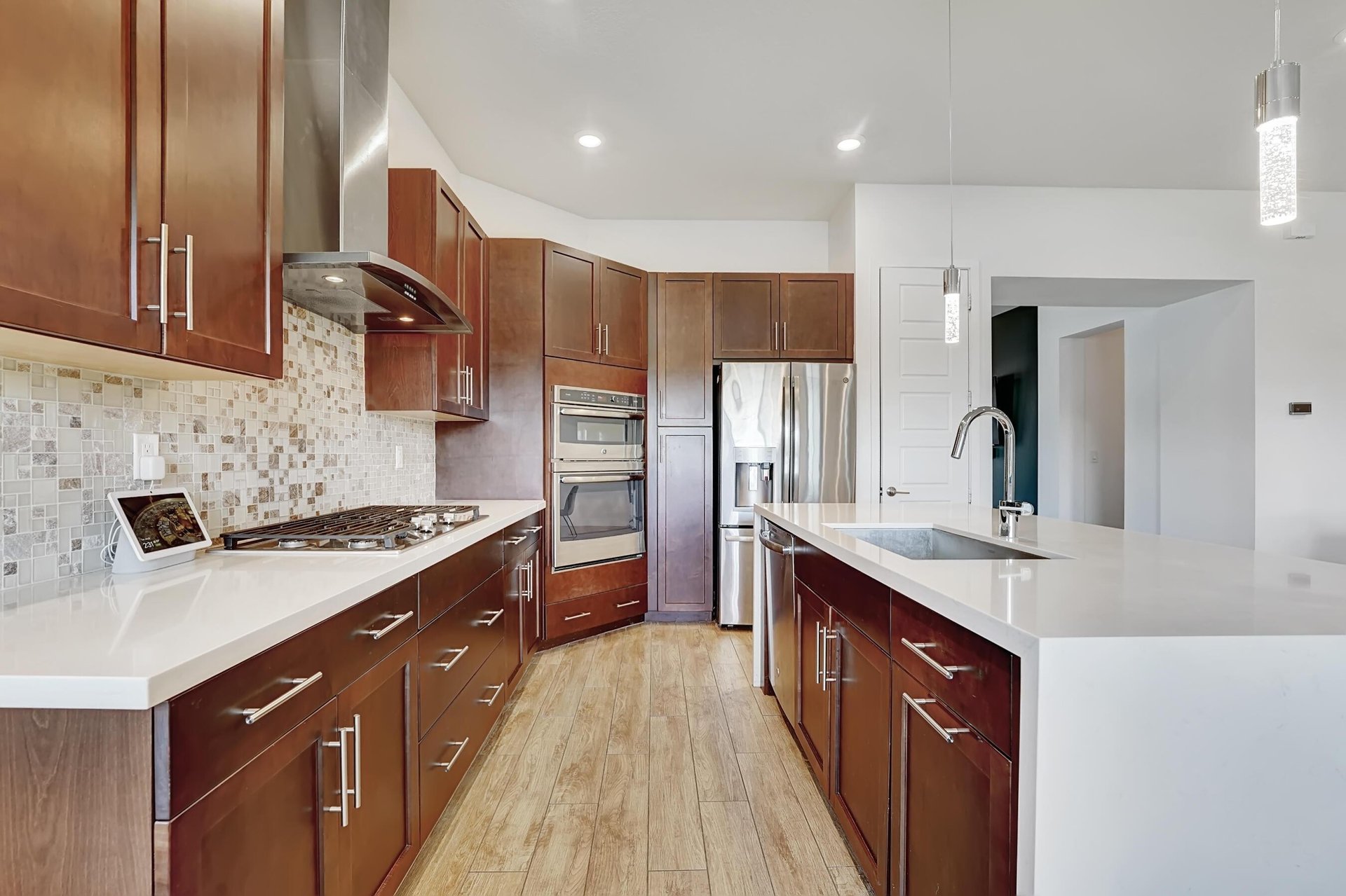 Kitchen with dark wood cabinetry, white countertops, and a large island with a sink.