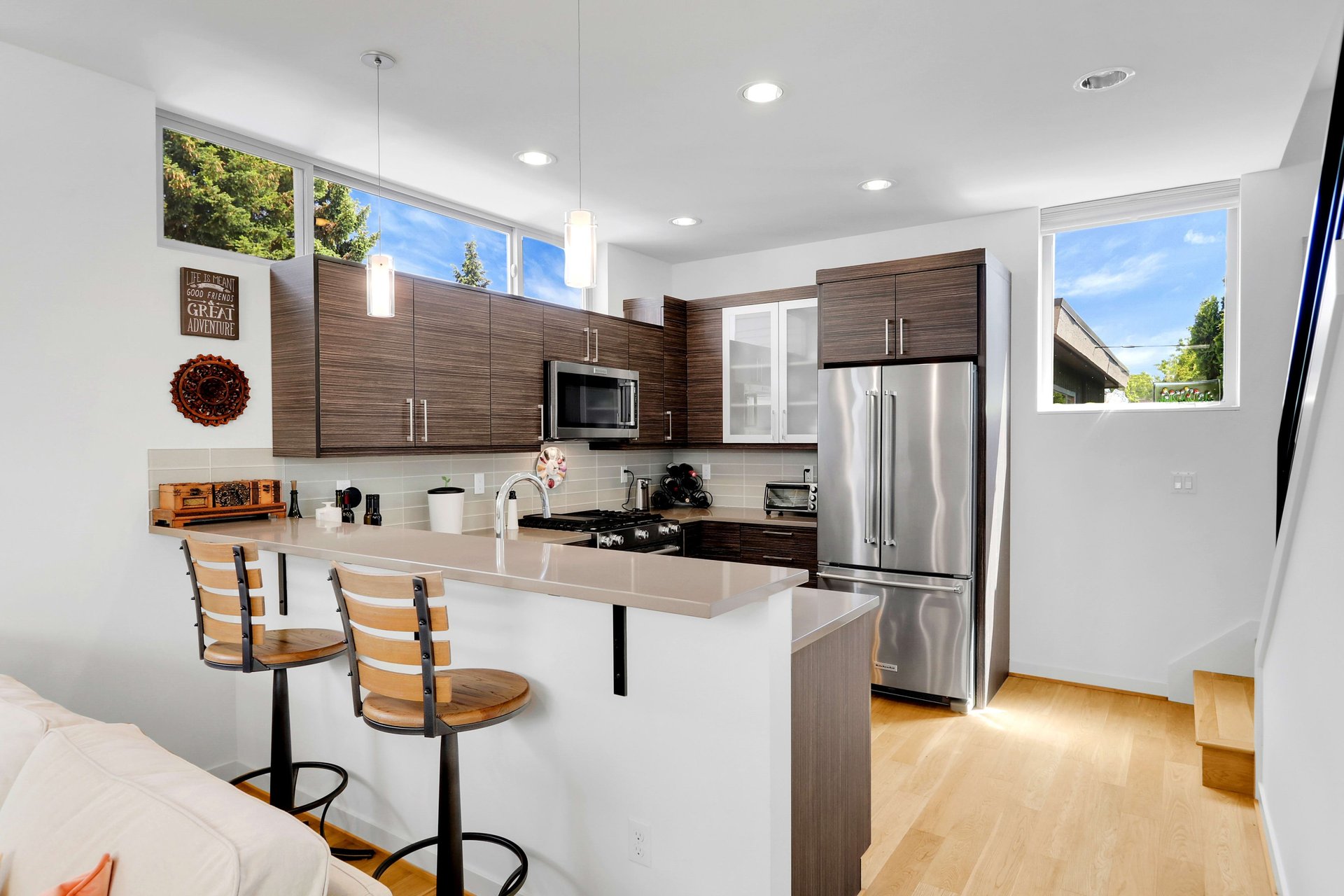 Kitchen with dark wood cabinets, stainless steel appliances, and a long peninsula with two bar stools.
