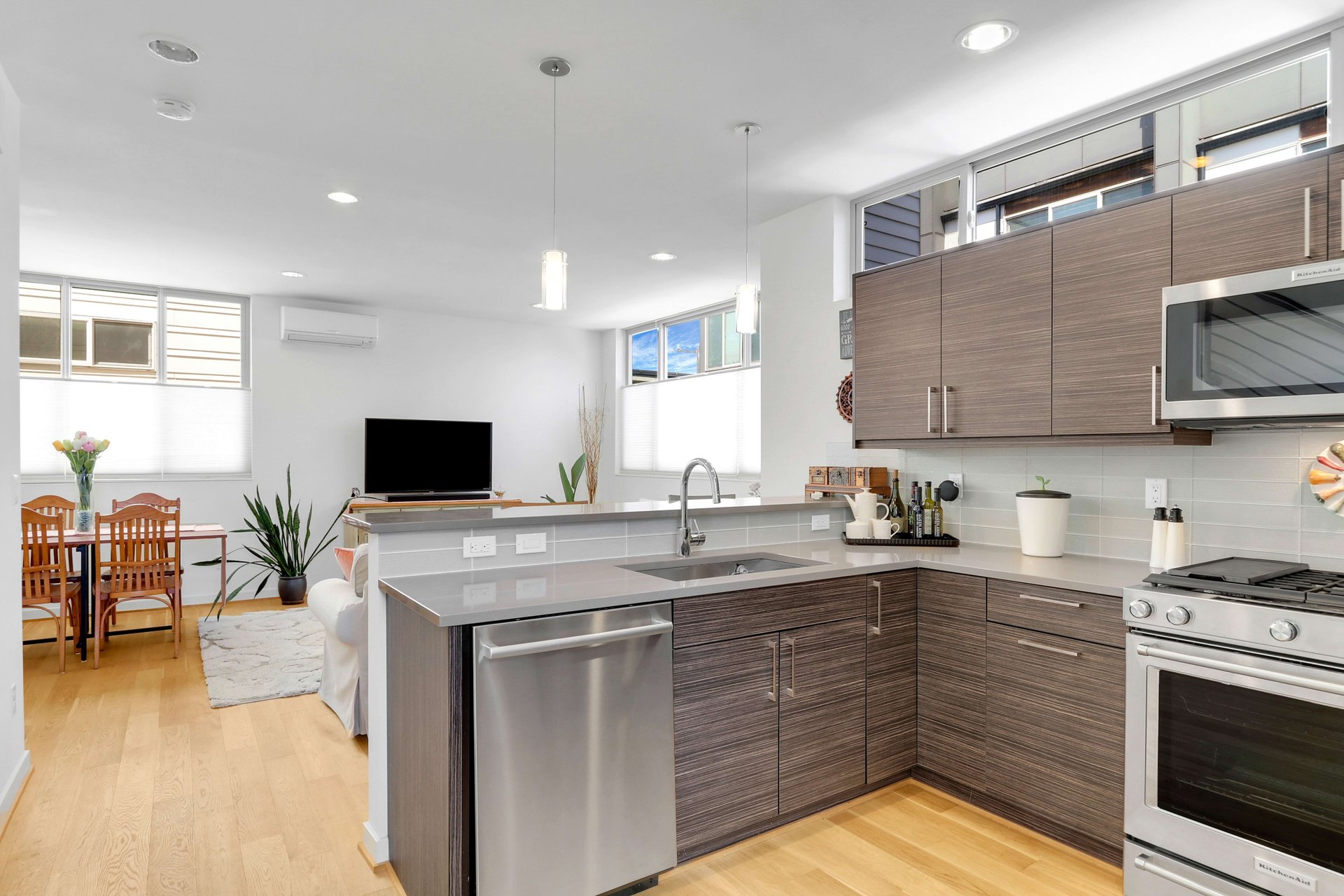 Open-plan kitchen with a gray island, dark wood cabinets, and stainless steel appliances.