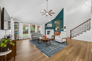 An open living area with vaulted ceiling and gas fireplace, naturally lit by a wall of windows