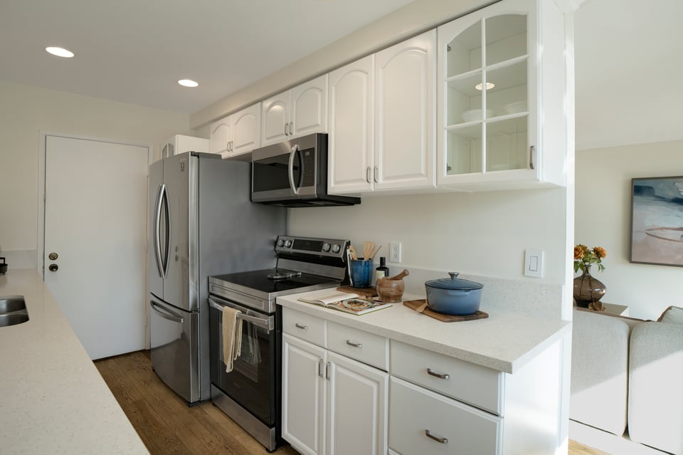 Kitchen with white cabinets, stainless steel appliances, and a blue pot on the counter.
