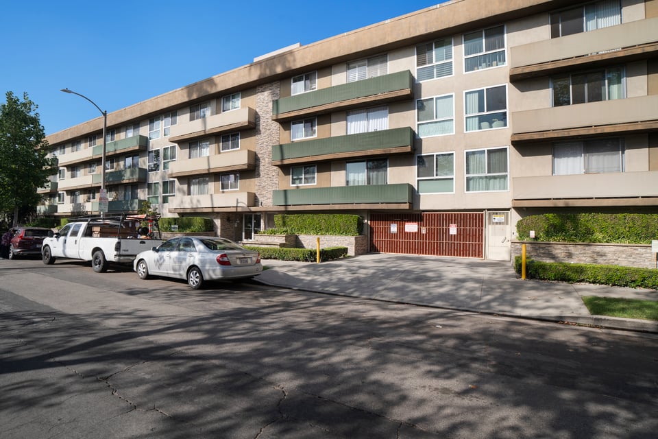 Apartment building with balconies and a gated garage entrance.