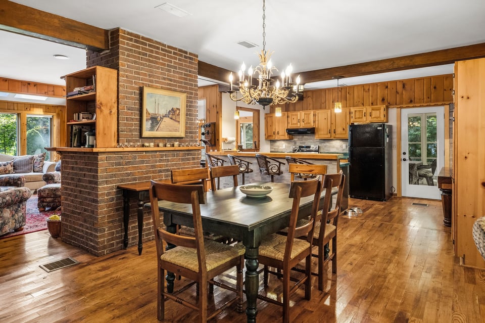 Wood-paneled kitchen and dining room with a brick fireplace and chandelier.