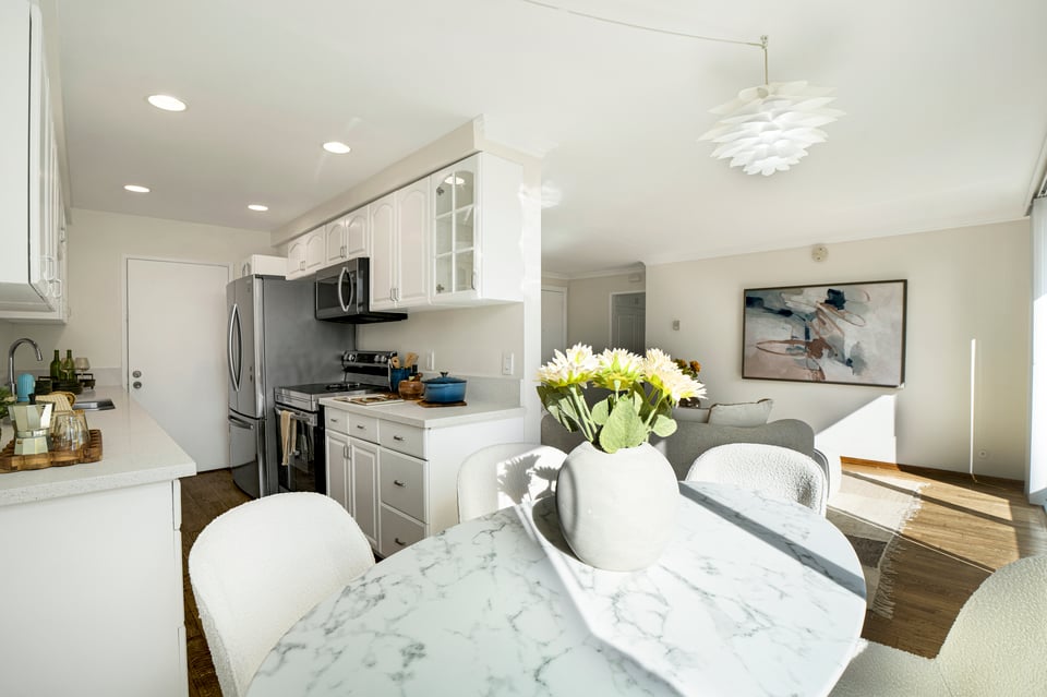 Open-plan kitchen and dining area with white cabinetry, stainless appliances, and a round table.