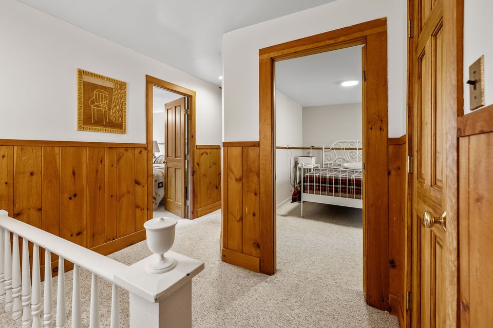 Upstairs hallway with wood paneling and open doorways to bedrooms.