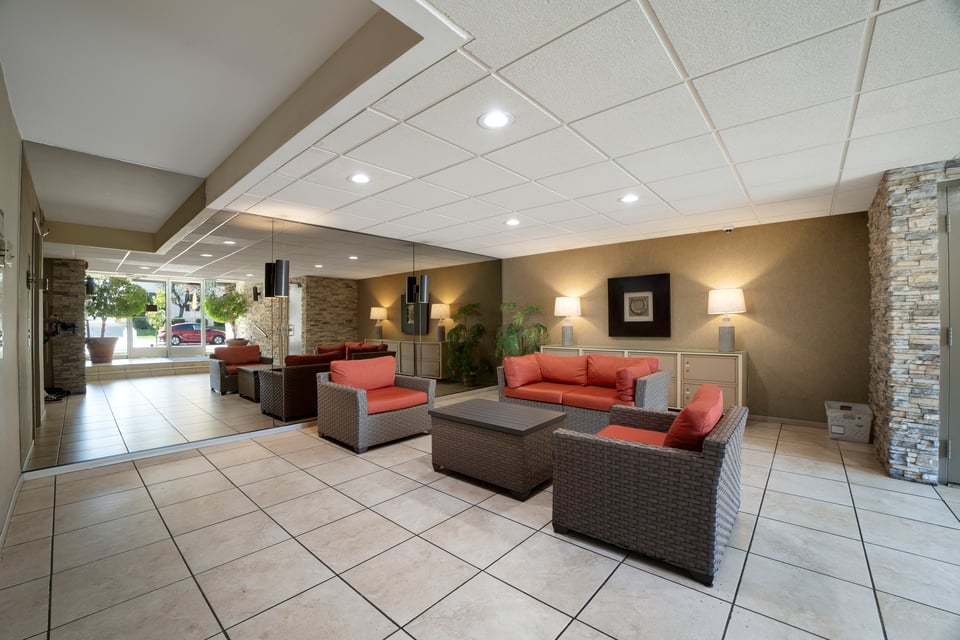Communal lounge with wicker seating, coral cushions, tiled floors, and stone accent walls.