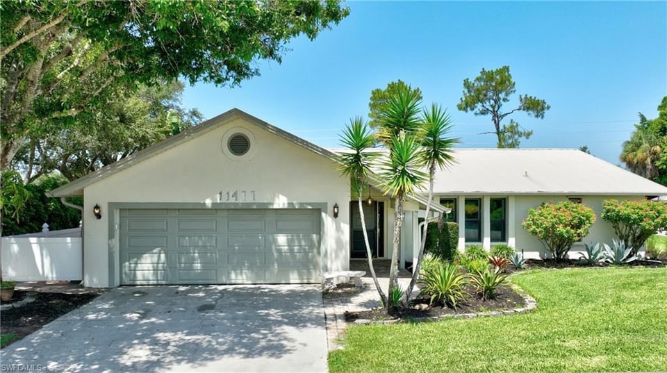 Single-story white house with a two-car garage and landscaped front lawn.