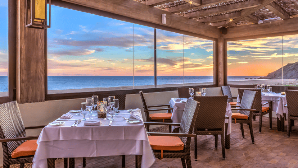 Oceanfront dining room set for dinner at sunset at Quivira