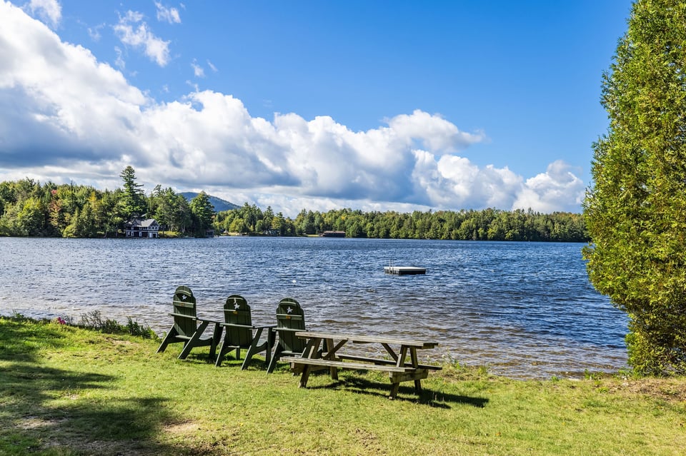 Lakeside lawn with Adirondack chairs and picnic table overlooking the water.