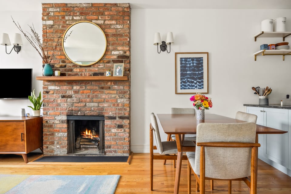 Living and dining area with a brick fireplace and hardwood floors.