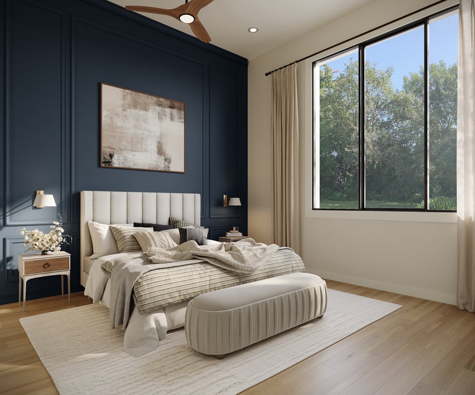 Staged bedroom with a cream upholstered bed, navy paneled wall, and large window overlooking trees.