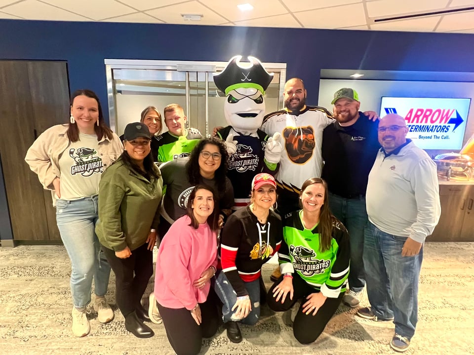 Eleven adults pose with a pirate mascot, several wearing Ghost Pirates jerseys.