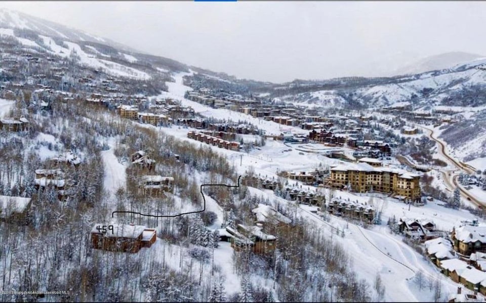 Aerial view of the snow-covered, wooded 459 property, outlined among buildings in a mountain valley.