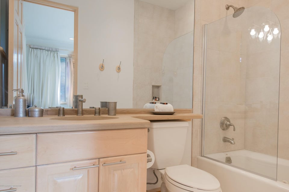 Bathroom with a light wood vanity and a glass-enclosed tub and shower.