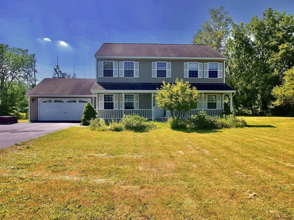 Two-story gray house with an attached garage, covered porch, and wide front lawn.