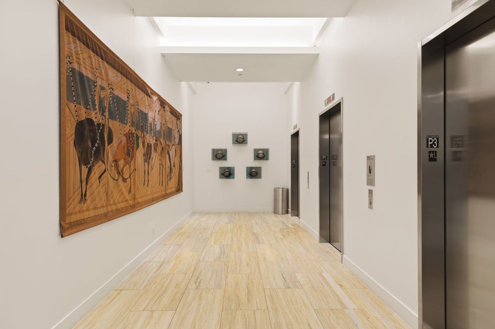 Gallery corridor at Bleu Ciel with a painted folding screen of horses and antique helmets on display