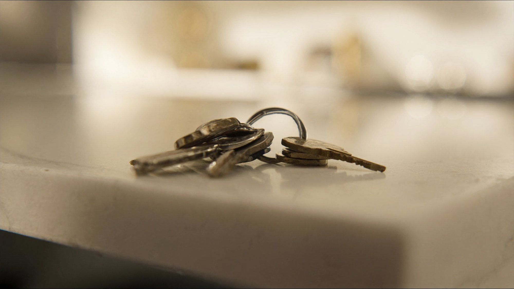 A set of house keys on a marble kitchen island in soft morning light
