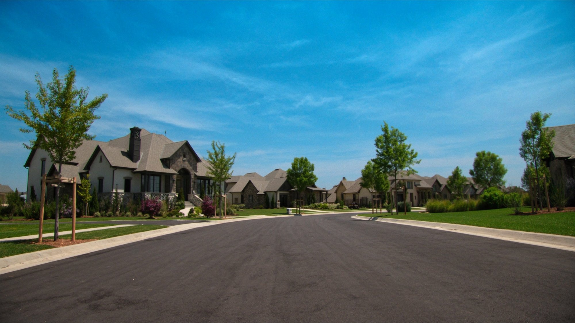 A newer neighborhood north of Dallas with stone homes along a curving street on a sunny day