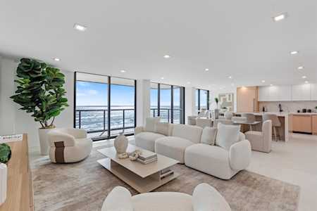 Open-plan living room with white sofas and floor-to-ceiling windows overlooking the ocean.