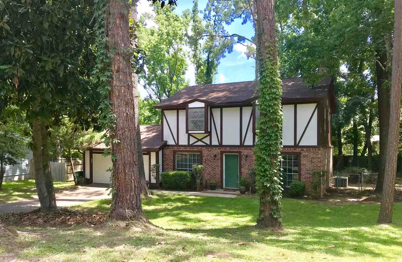 A spacious house surrounded by a large yard and several trees, creating a serene and inviting outdoor environment.