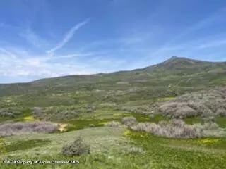 Rolling sagebrush hills beneath a blue, cloud-streaked sky.