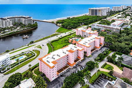 Aerial view of pink condominium buildings beside a waterway near the ocean.