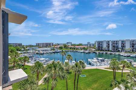 East Boca marina with boats, waterfront condos, palm trees and a green lawn.