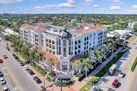 Aerial view of a multi-story building with red tile roofs and palm-lined streets.