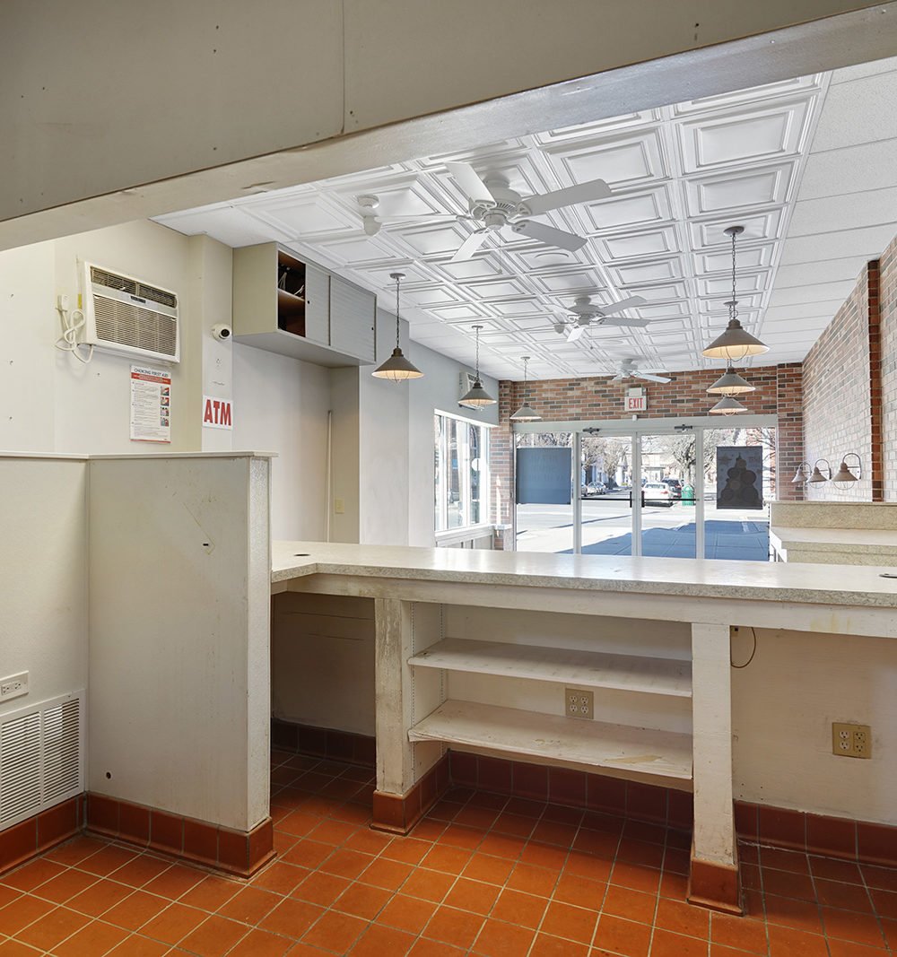 Vacant commercial interior with a service counter, terracotta tile floor, brick walls, and decorative ceiling.