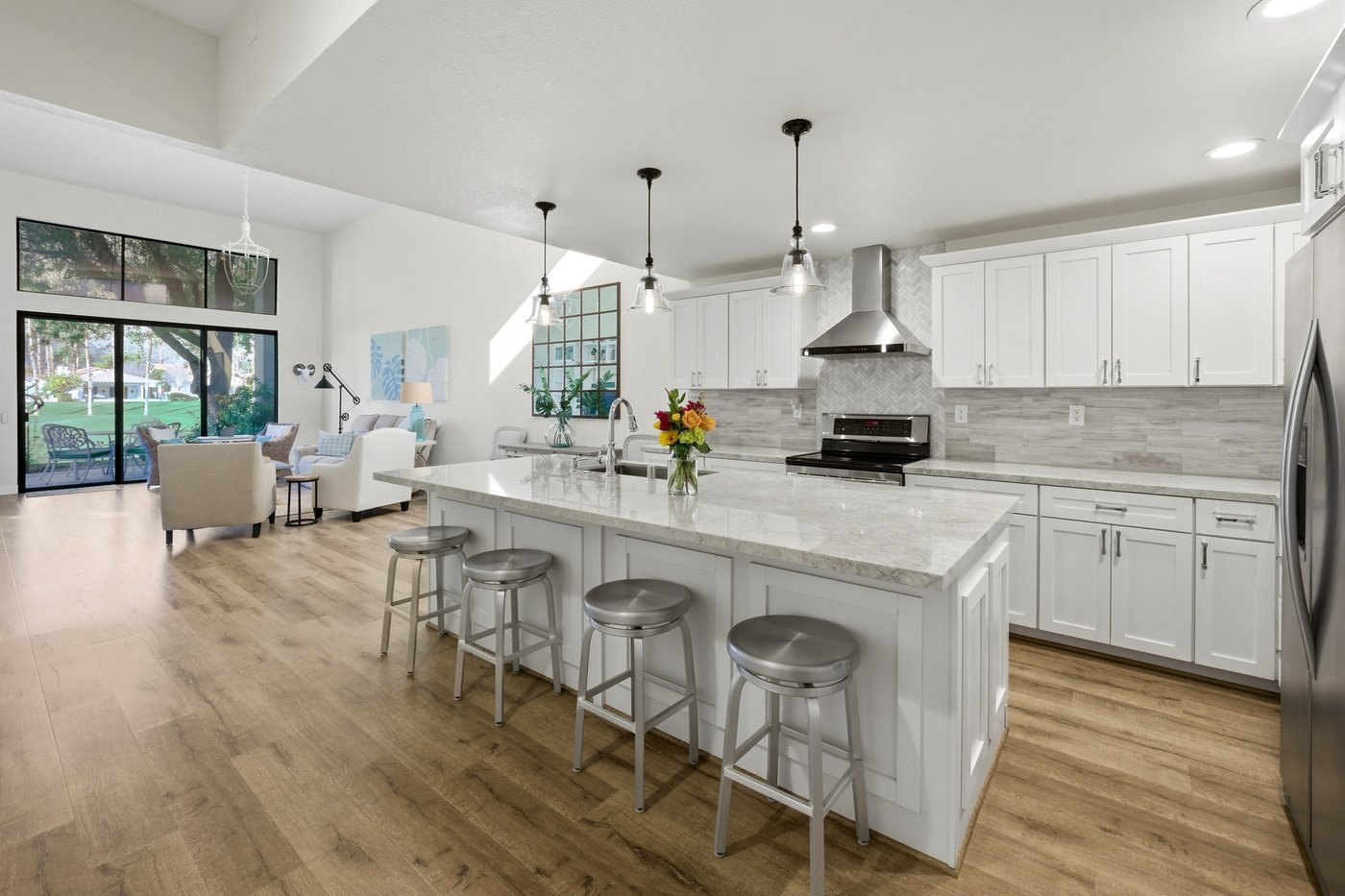 Wide-angle white kitchen with marble island and pendant lights at a PGA West home