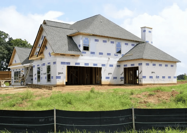 New-construction house with multiple gables, exposed openings, and white house wrap.