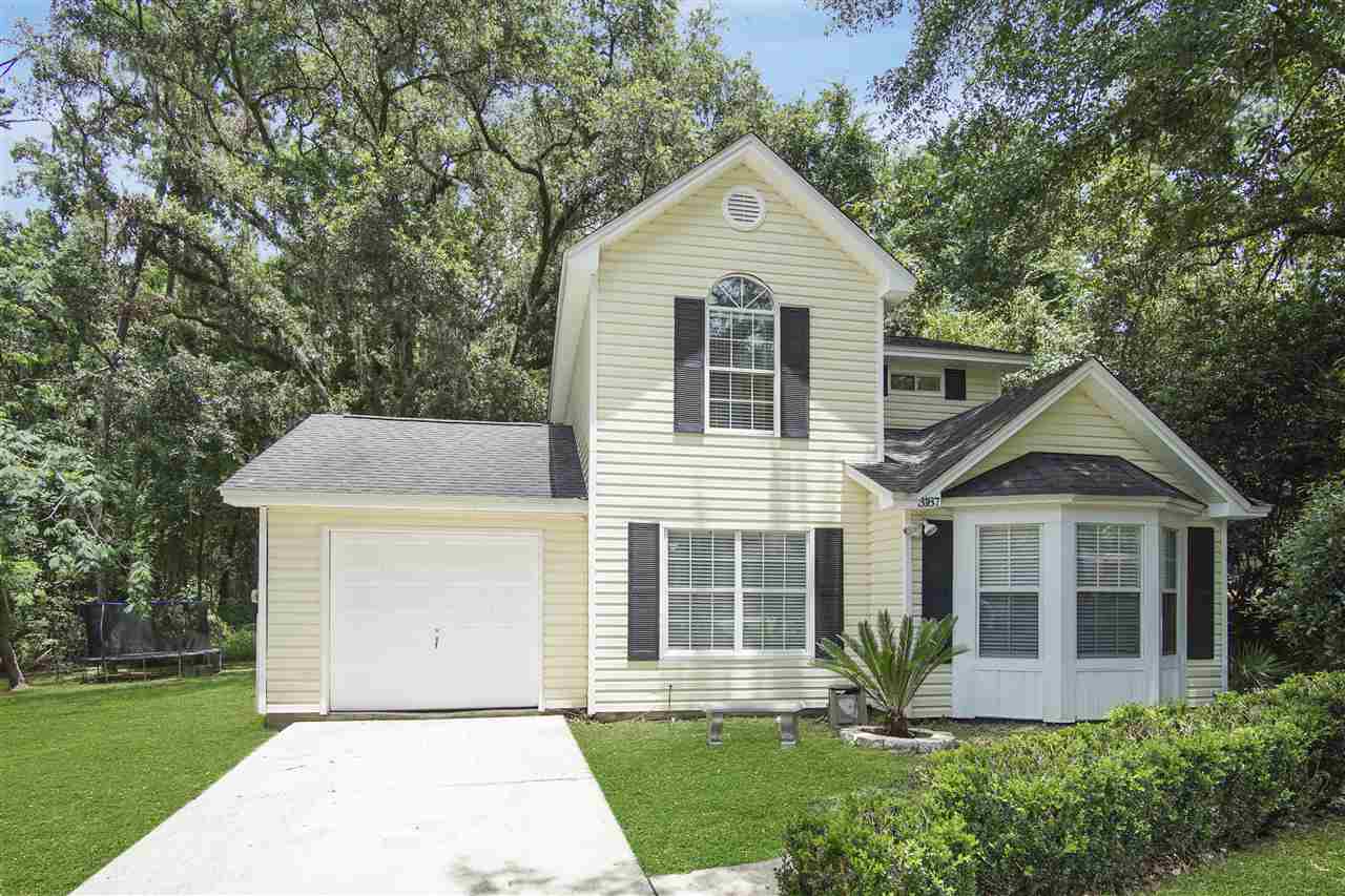 A small house featuring a garage and a driveway, set in a serene residential area.