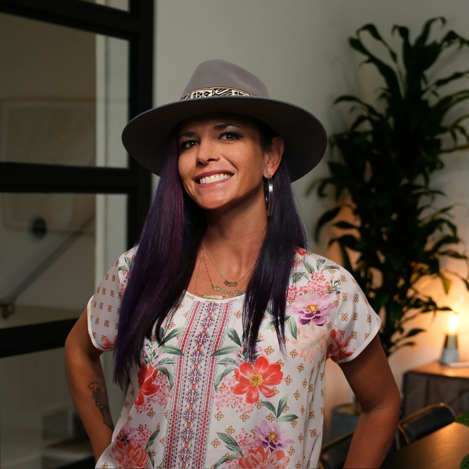 Hilary Saunders smiles in a gray hat and floral blouse.