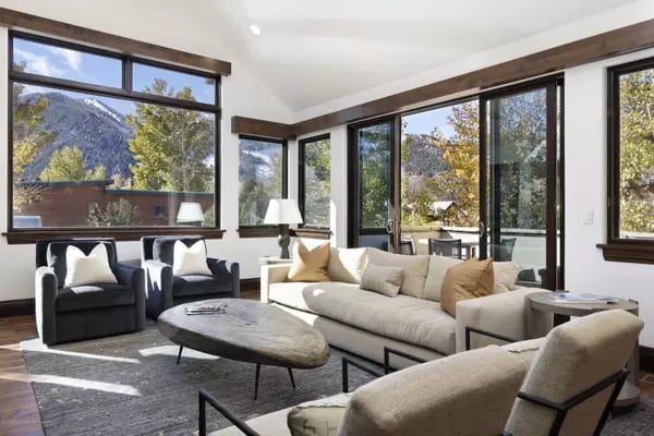 Living room with a cream sofa and mountain views through large windows.